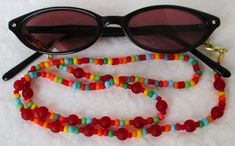 Always keep your reading glasses nearby - use this red/multicolor beaded eyeglass chain! 25.5" in length, made with glass beads, beading cord, metal lobster clasps, and adjustable rubber holders. Lobster clasps make it easy to change the rubber holders, and an extra pair of holders included with every purchase. This bold red/multicolor beaded eyeglass chain will arrive in a gift box, ready to give as a present or to keep and store. Back to Beaded Eyeglass Chains Adjustable Round Bead Glass Necklaces, Adjustable Czech Glass Beaded Necklaces With Lobster Clasp, Adjustable Single Strand Glass Beaded Necklaces, Adjustable Single Strand Glass Beaded Necklace, Red Adjustable Beaded Necklaces With Spacer Beads, Adjustable Red Czech Glass Beads, Red Beaded Glasses Chains As Gift, Red Beaded Glasses Chains For Gift, Adjustable Single Strand Red Beads