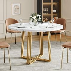 a white marble dining table with gold metal legs and four beige chairs in a living room