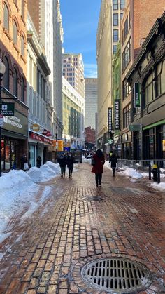 people walking down a street in the middle of winter with lots of snow on the ground