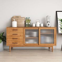 a wooden cabinet with glass doors next to a potted plant and a painting on the wall