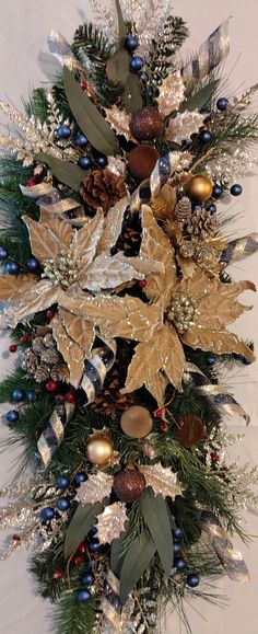 a christmas wreath with gold and silver decorations on it's sides, hanging from the ceiling