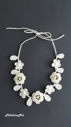 a white necklace with crocheted flowers on it