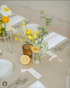 the table is set with yellow and white flowers in vases, silverware, and napkins