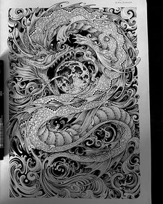 an intricate drawing on top of a book next to a pen and ink rollers