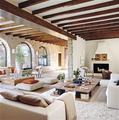 a living room filled with lots of white furniture and large arched windows over the fireplace