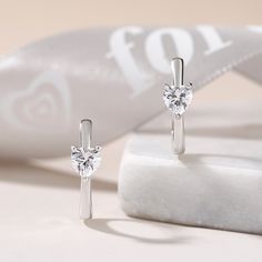 Sweet and sparkling, these simple hoop earrings relay your affection. Fashioned in fine sterling silver, these charming hoops are set with a shimmering heart cut stone, adding a hint of glimmer. A small heart design is set on the earring, lending it a clean and classical look.Carat Weight: 1.6 ctStone Size: 5*5 mmStone Type: Jeulia® StoneNumber of Stones: 2 Stone Color: Diamond WhiteStone Shape: HeartWeight: 2.9 gWidth: 5.1 mmHeight: 6.3 mmThickness: 3.7 mmMaterial: 925 SilverPlating Color: Silv Elegant Huggie Earrings With Heart Charm For Anniversary, Elegant Heart Charm Huggie Earrings For Anniversary, Elegant Sterling Silver Huggie Earrings With Heart Charm, Elegant Anniversary Huggie Earrings With Heart Charm, Elegant Silver Huggie Earrings With Heart Charm, Silver Elegant Huggie Earrings With Heart Charm, Anniversary Heart-shaped Hoop Earrings With Heart Charm, Minimalist Heart-shaped Huggie Earrings For Anniversary, Elegant Silver Huggie Heart Earrings