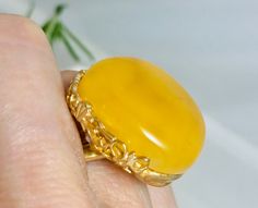 An absolutely gorgeous ring is created of genuine Baltic amber of rich Yellow / Butterscotch color.Beautiful amber gemstone framed in a handcrafted detailed floral style design silver frame plated in 18K Gold. Luxurious and unusual amber jewelry ring is absolutely impressive.This ring is fully adjustable with incomplete ring band.Amber is product of nature a tru historic time capsule created over 45 million years ago. Material: Genuine baltic amber/ Silver/ gold 18K plated Dimensions   :  25 x 2 Elegant Amber Cabochon Ring, Unique Amber Rings For Formal Occasions, Formal Amber Rings, Elegant Yellow Oval Cabochon Ring, Yellow Oval Cabochon Ring For Gift, Luxury Yellow Rings For Collectors, Unique Yellow Baltic Amber Jewelry, Yellow Oval Cabochon Gemstone Jewelry, Heirloom Amber Rings For Formal Occasions