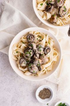 two white bowls filled with pasta and mushrooms