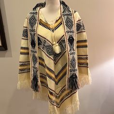 Made In Ecuador- This Beautiful Poncho Is Nwot - No Size Label - Medium 100% Wool Tassel Tie At Neck And 4” Wide Attached Scarf Tassel Trim Hem All Around Cream Background With Black Yellow Brown Orange Pattern Woven Throughout Fun Addition To Your Wardrobe - Keeps You Warm And Finishes Off Your Outfit! Length 38.5” To Longest Point Including Tassels Bin 2 Beige Long Sleeve Bohemian Cape, Cream Bohemian Poncho Shawl, Bohemian Cream Shawl Poncho, Bohemian One Size Cream Poncho, Bohemian Yellow Poncho One Size, Yellow Bohemian Poncho One Size, Cream Bohemian Shawl For Fall, Yellow Bohemian Poncho For Fall, Yellow Bohemian One-size Poncho