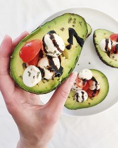 someone is holding an avocado that has been cut in half and placed on a plate