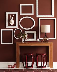 there are many frames on the wall and two stools in front of them,