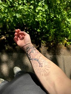 a man with a tattoo on his arm is sitting in front of some bushes and trees