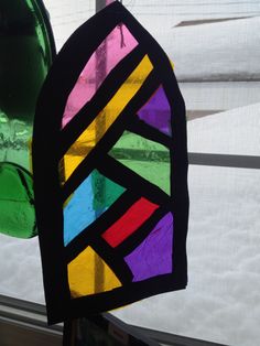 a stained glass window with a green vase next to it