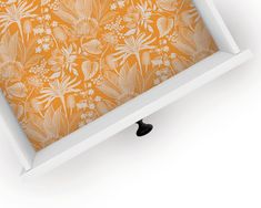 an orange and white floral wallpaper with black knobs in a white frame on the floor