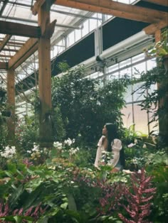 a woman standing in a greenhouse surrounded by plants