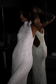 a woman in a white dress looking into a mirror