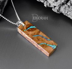 a wooden pendant with blue glass inlays on a silver plated necklace chain