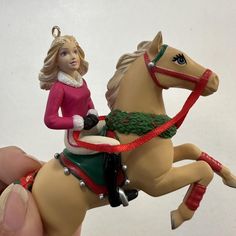 a hand holding a christmas ornament with a horse on it's back