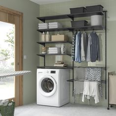 a washer sitting next to a dryer in a room with shelving on the wall