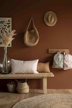 a wooden bench with pillows and hats on the wall above it, along with other items