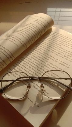 an open book with glasses on top of it next to a pair of reading glasses