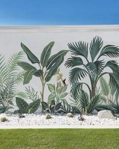 a large mural on the side of a building with plants and rocks in front of it