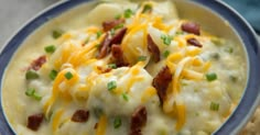 a blue and white bowl filled with macaroni and cheese covered in green onions