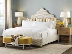 a bedroom with blue walls, white bedding and yellow foot stools in front of the bed