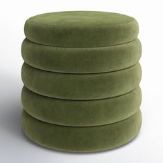 a stack of green round cushions sitting on top of a white floor next to each other