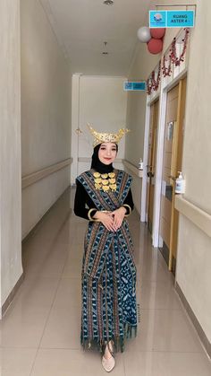 a woman wearing a crown and dress standing in a hallway with her hands on her hips