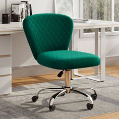 a green office chair sitting in front of a desk with a white table and drawers