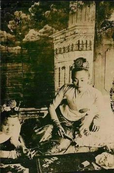 an old black and white photo of a woman sitting on the ground with two children