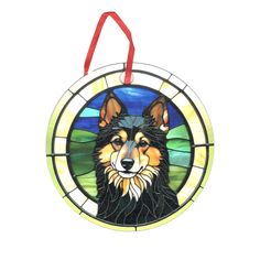 a stained glass ornament with a dog's face in the center and a red ribbon hanging from it