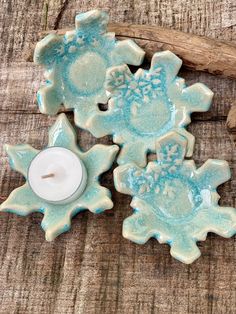 three ceramic snowflakes with a candle on a wooden table