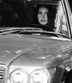 a woman sitting in the passenger seat of a car with her head out the window