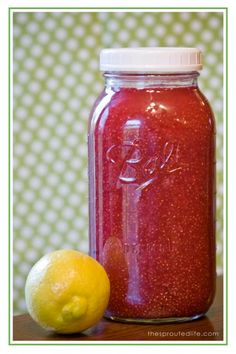 a lemon next to a mason jar filled with red liquid and sitting on a table