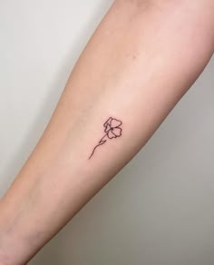 a small flower tattoo on the left forearm and right arm is shown in black ink