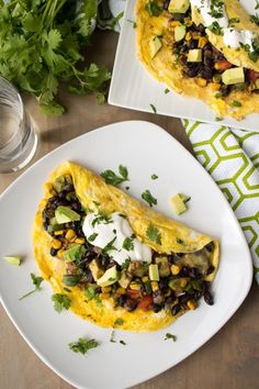 an omelet with black beans, avocado and sour cream on top