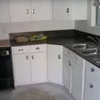 an empty kitchen with white cabinets and black counter tops is seen in this image from the front view