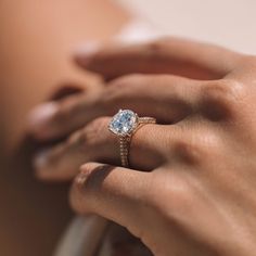 a woman's hand with a diamond ring on her left hand and the other hand holding an engagement ring