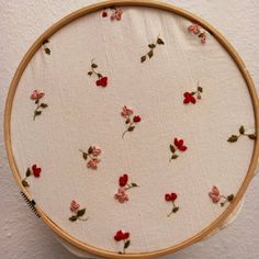 a close up of a embroidery on a hoop with red and pink flowers in it