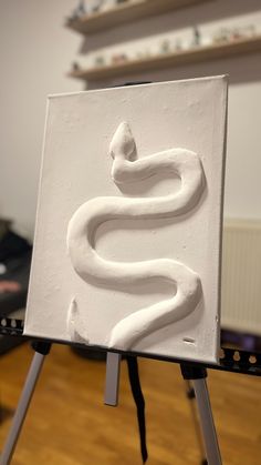 a white sculpture sitting on top of a easel in front of a wooden floor