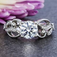 a diamond ring sitting on top of a table next to some purple and white flowers