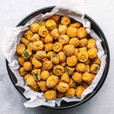 a black bowl filled with fried food on top of a white tablecloth next to a spoon