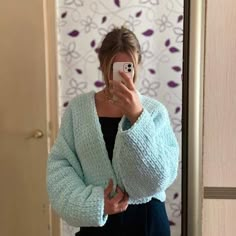 a woman taking a selfie in front of a mirror wearing a blue cardigan