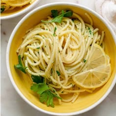 two bowls filled with pasta and lemon slices