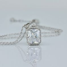 "Classically elegant and sophisticated! Emilia cz crystal bridal necklace made in a radiant cut with a frame of tiny cz crystals for a beautiful sparkling accessory that will suit your dress, whatever style. The 18K rhodium setting has delicate carving around the sides so your necklace is pretty from all aspects! All components are rhodium plated sterling silver. Nickel free. Rhodium plating helps prevent issues with silver allergies. Measurements: Chain - With extender measures 16\" - 18\" (41 Luxury Square Pendant Solitaire Necklace For Gift, Formal Emerald-cut Solitaire Necklace In Cubic Zirconia, Formal Emerald Cut Solitaire Necklace With Cubic Zirconia, Emerald Cut Cubic Zirconia Diamond Necklace For Wedding, Wedding Solitaire Necklace With Brilliant Radiant Cut, Silver Emerald Cut Solitaire Necklace For Wedding, Emerald Cut Cubic Zirconia Solitaire Necklace For Wedding, Radiant Cut Solitaire Necklace In White Gold For Wedding, White Gold Radiant Cut Solitaire Necklace For Wedding