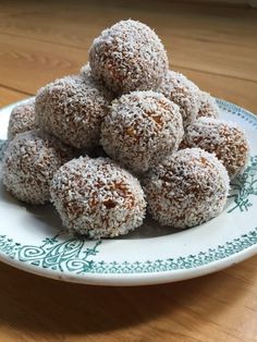 a white plate topped with lots of powdered sugar covered doughnuts on top of a wooden table