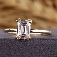 an emerald - cut diamond ring sits on top of a blanket