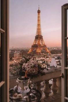 the eiffel tower is lit up at night from an open window with a view